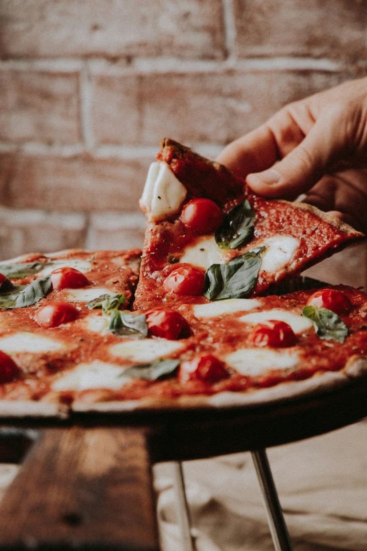 Mano che prende una fetta di pizza