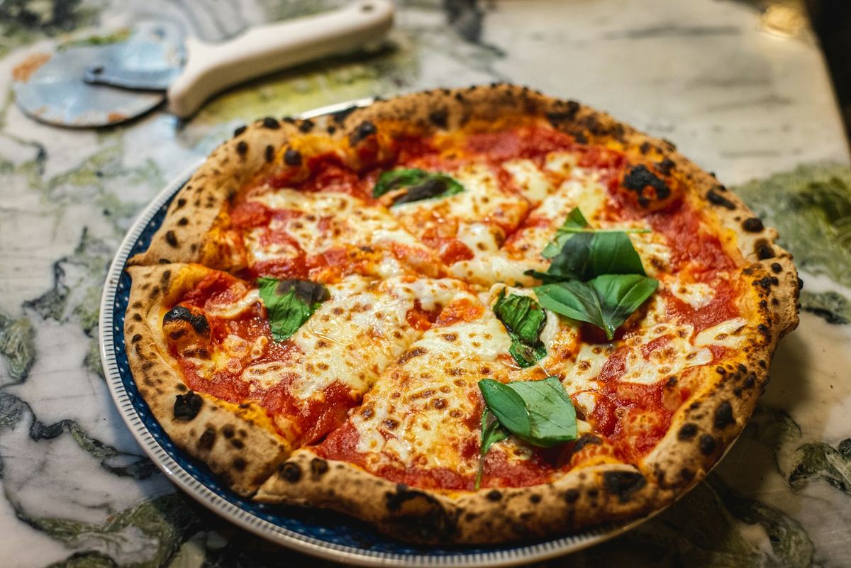 Pizza margherita su un piatto, con la rotella accanto