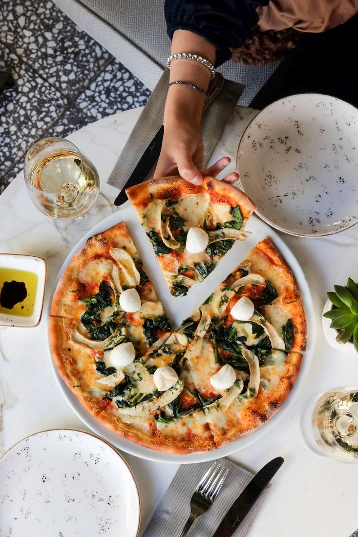 Tavola apparecchiata con una pizza al centro, vista dall'alto